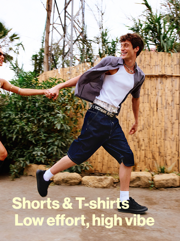 Model v bílém tílku, košili s krátkým rukávem a dlouhých šortkách; text Shorts & T-shirts Low effort, high vibe.